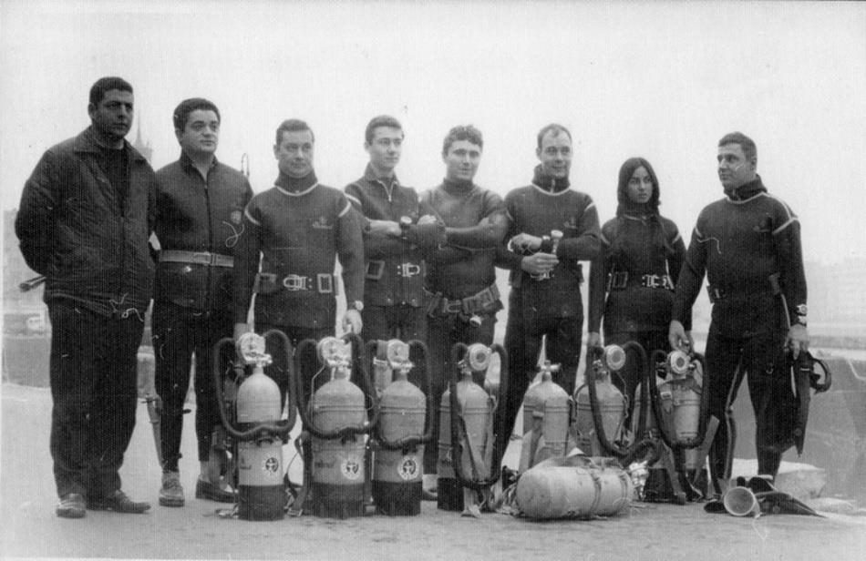 Grupo de ocho buceadores con botellas de aire comprimido posando en un muelle